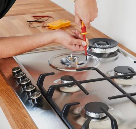 Technician repairing a gas cooktop burner